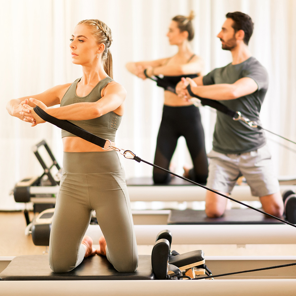 Teilnehmende beim Reformer Pilates mit Zugbändern und kontrollierter Körperspannung