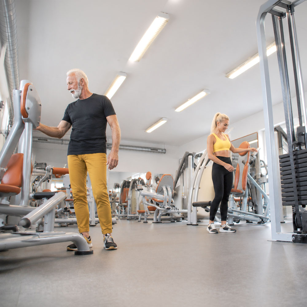 Älterer Mann und junge Frau sehen sich Fitnessgeräte im Studio in Weißwasser an